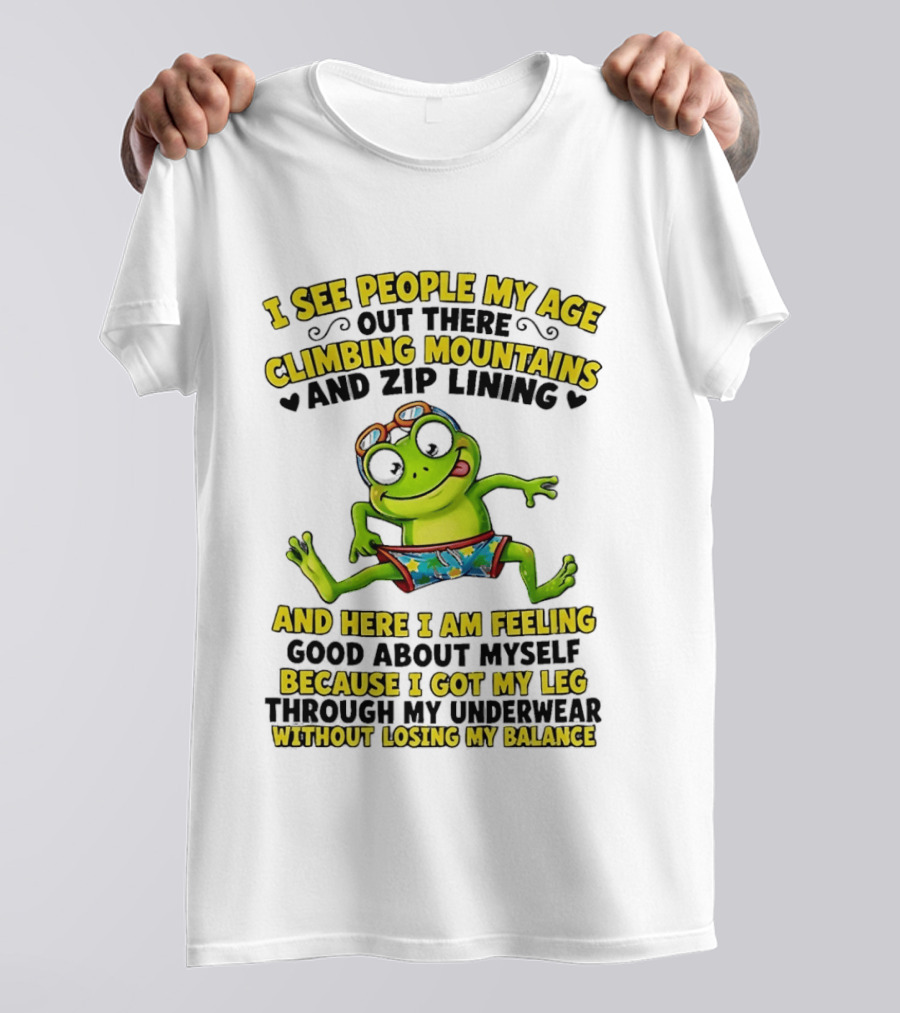 I See People My Age Climbing Mountains And Zip Lining Cartoon Frog Feeling Good Without Losing Balance T-Shirt